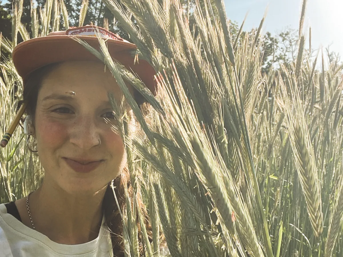 Abby standing in the rye and vetch cover crop at Little Bend, stalks chest-high in late spring sun.